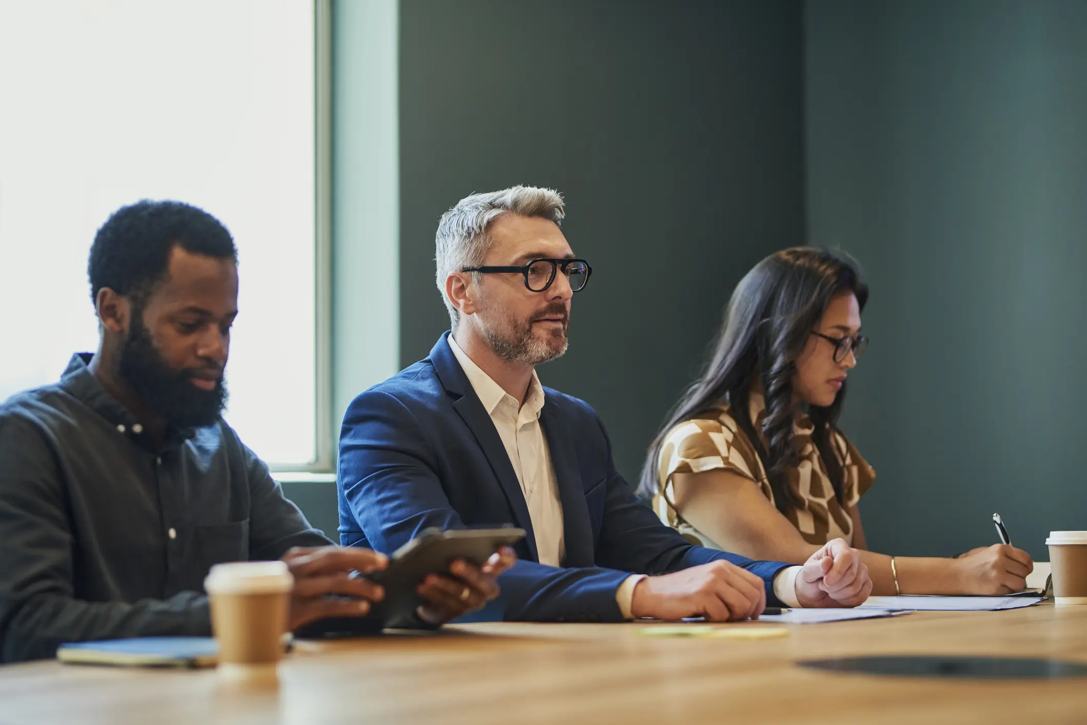 Three professionals seated and focused during a meeting.