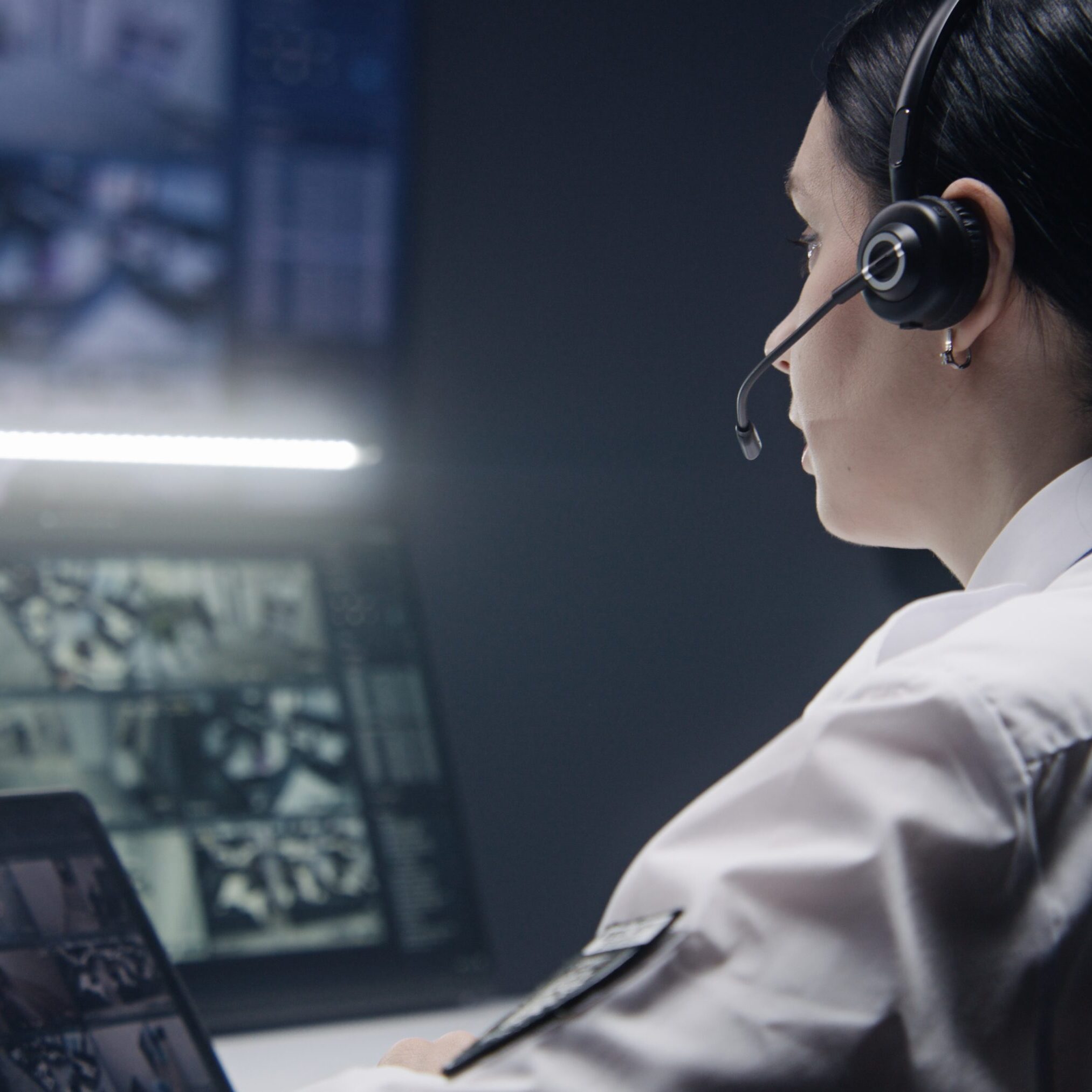 A call center agent wearing a headset works at a computer with multiple screens.